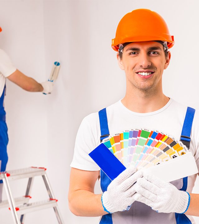 To make repairs. Young designers men in working clothes, make repairs in the room.