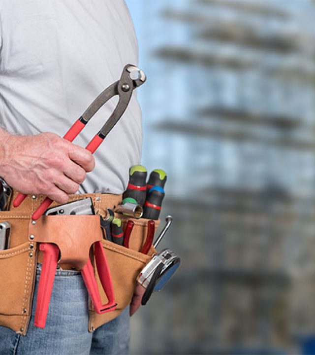 Building worker with tool belt on a construction site background