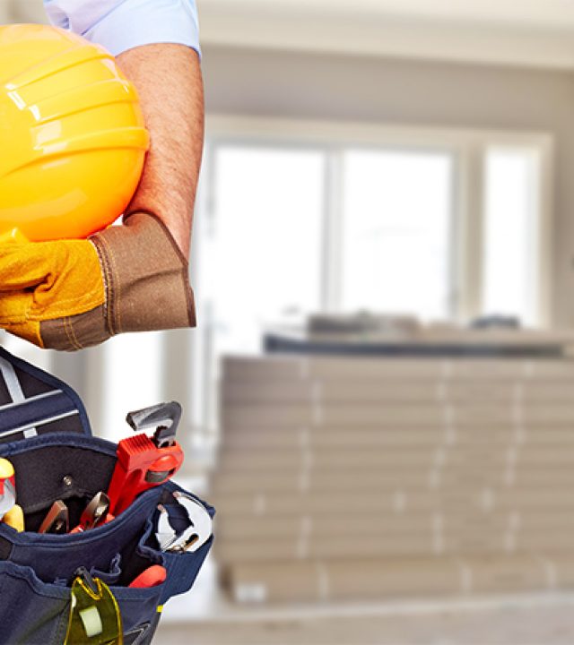 Builder handyman with construction tools. House renovation background.