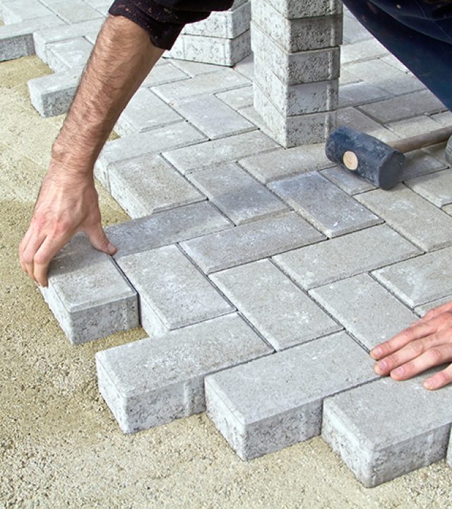 Bricklayer prfessional at work on the sidewalk saves tiles.